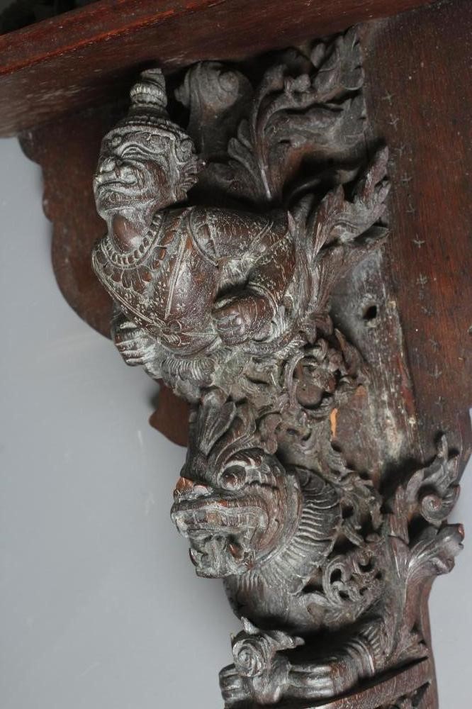 AN EASTERN HARDWOOD APPLIQUE intricately carved with a half length grimacing male figure over a Image
