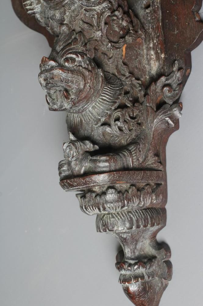 AN EASTERN HARDWOOD APPLIQUE intricately carved with a half length grimacing male figure over a Image