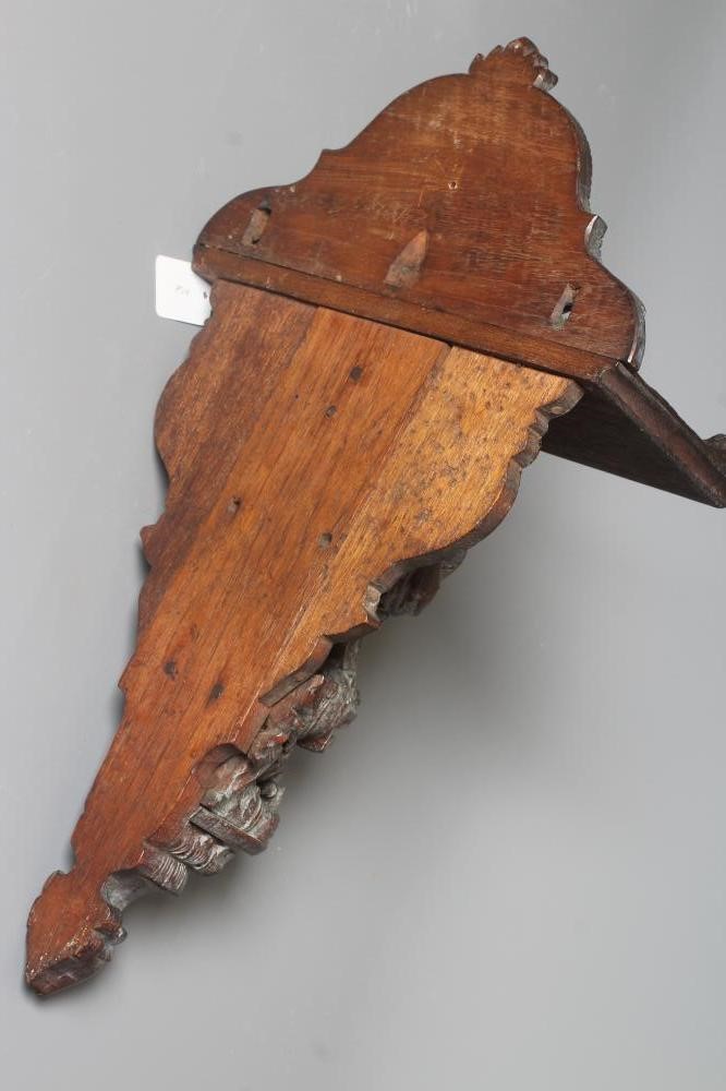 AN EASTERN HARDWOOD APPLIQUE intricately carved with a half length grimacing male figure over a Image
