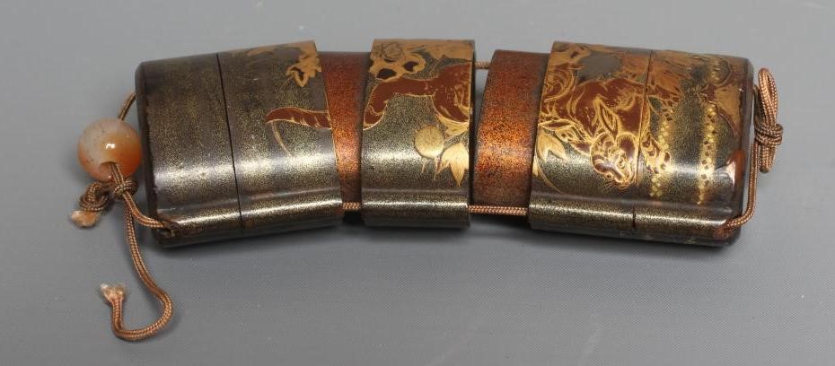 A JAPANESE LACQUER FOUR CASE INRO with two Temple Dogs in landscape on a dark green ground Image