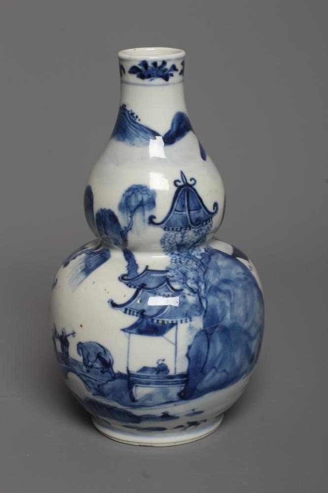 A CHINESE PORCELAIN GOURD VASE painted in underglaze blue with a river landscape with two figures Image