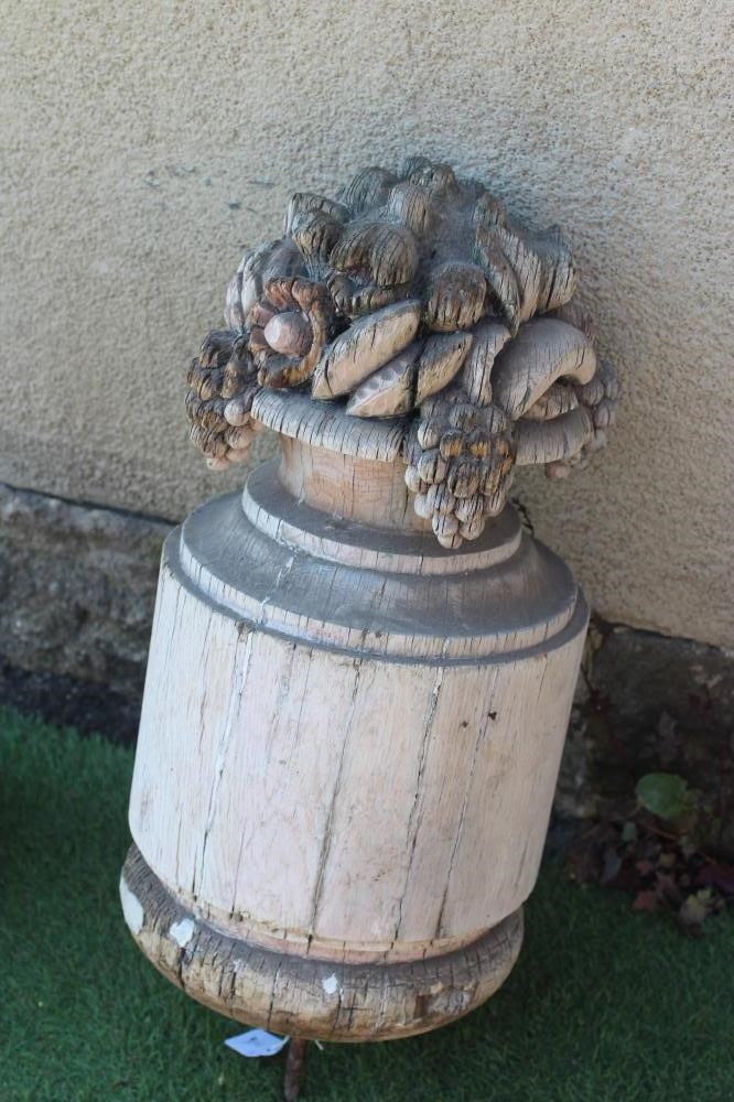 A CARVED SOFTWOOD CYLINDRICAL FINIAL surmounted by a vase of fruit, 25" high (excluding spike), Image