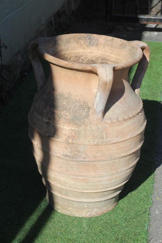 A TERRACOTTA THREE HANDLED VASE with flared rim, the ovoid body with cable twist and ribbed banding, Image