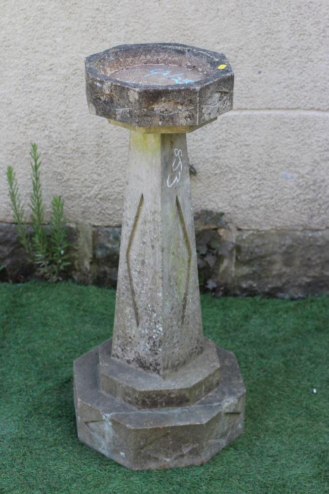 AN ART DECO STYLE HEXAGONAL SANDSTONE BIRDBATH with square tapering stem and carved with recessed Image