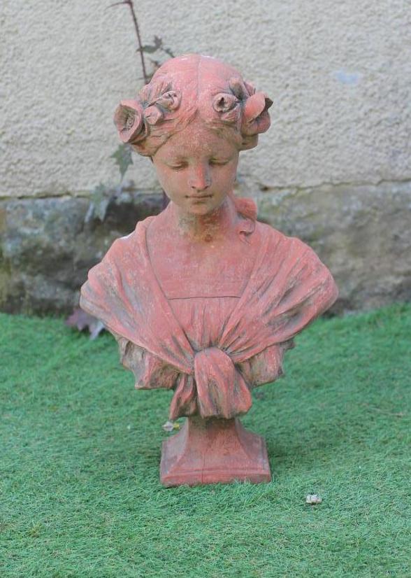 A TERRACOTTA BUST OF A YOUNG MAIDEN modelled with flowers in her tied-up hair, on waisted square Image