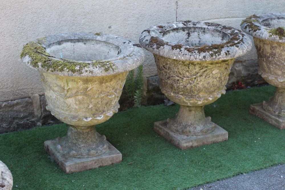 A set of four cast stone urns with everted rim over a body with ...