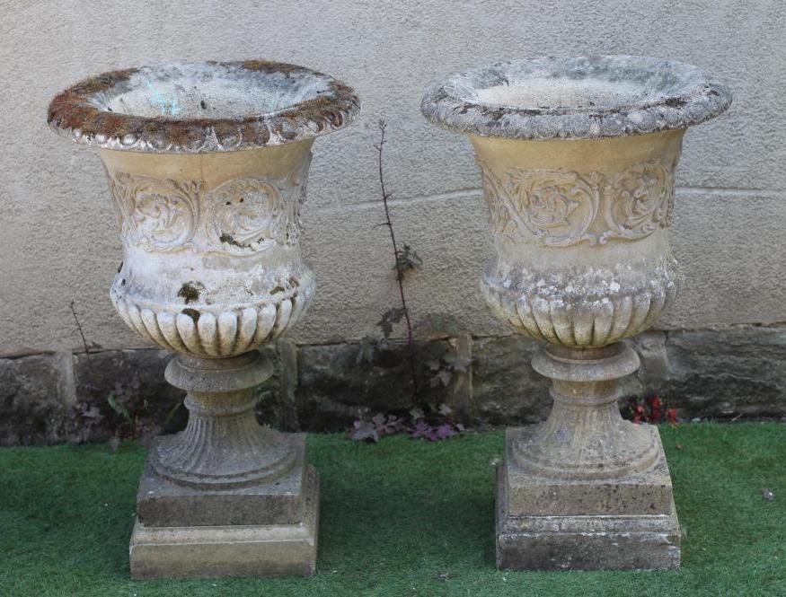 A PAIR OF CAST STONE URNS of semi fluted campana form, the ovolu rim over a body with scrolling Image