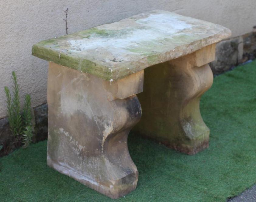 A SANDSTONE BENCH, the oblong seat with rough-hewn edge raised on square section scrolled fronted Image