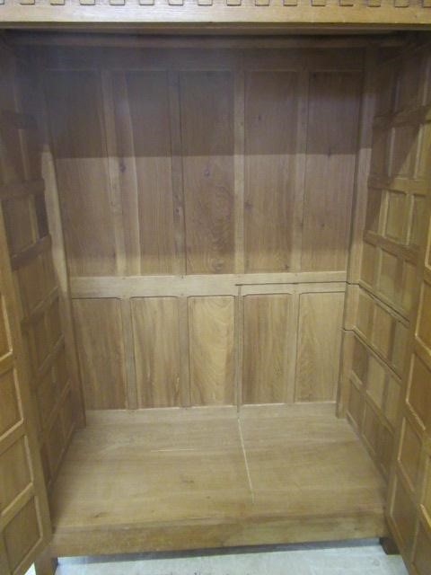 A ROBERT THOMPSON ADZED OAK DOUBLE WARDROBE of multi-panelled form with half penny moulded cornice Image