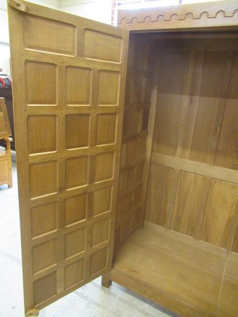 A ROBERT THOMPSON ADZED OAK DOUBLE WARDROBE of multi-panelled form with half penny moulded cornice Image