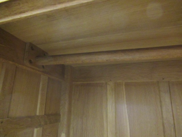 A ROBERT THOMPSON ADZED OAK DOUBLE WARDROBE of multi-panelled form with half penny moulded cornice Image