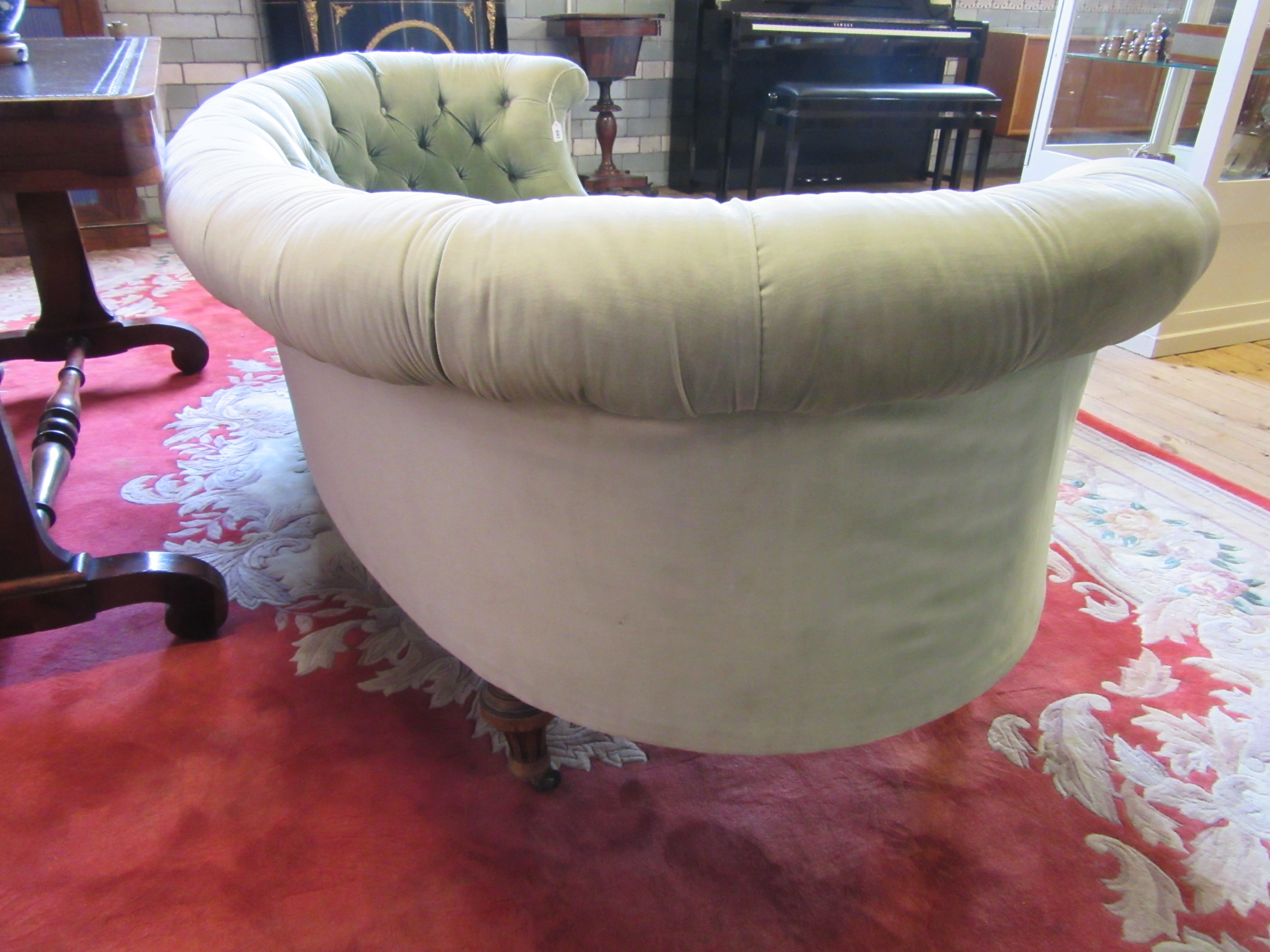 A VICTORIAN WALNUT FRAMED CHESTERFIELD SOFA of curved outline button upholstered in pale green Image