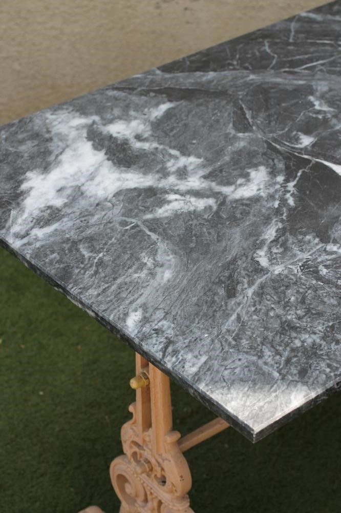 A GARDEN TABLE comprising a veined grey marble top on a Victorian cast iron base Image