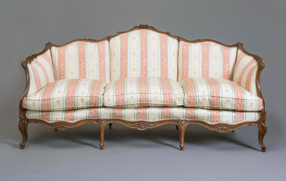 A LOUIS XVI STYLE WALNUT FRAMED SOFA of serpentine outline carved with flowers and scroll work and Image