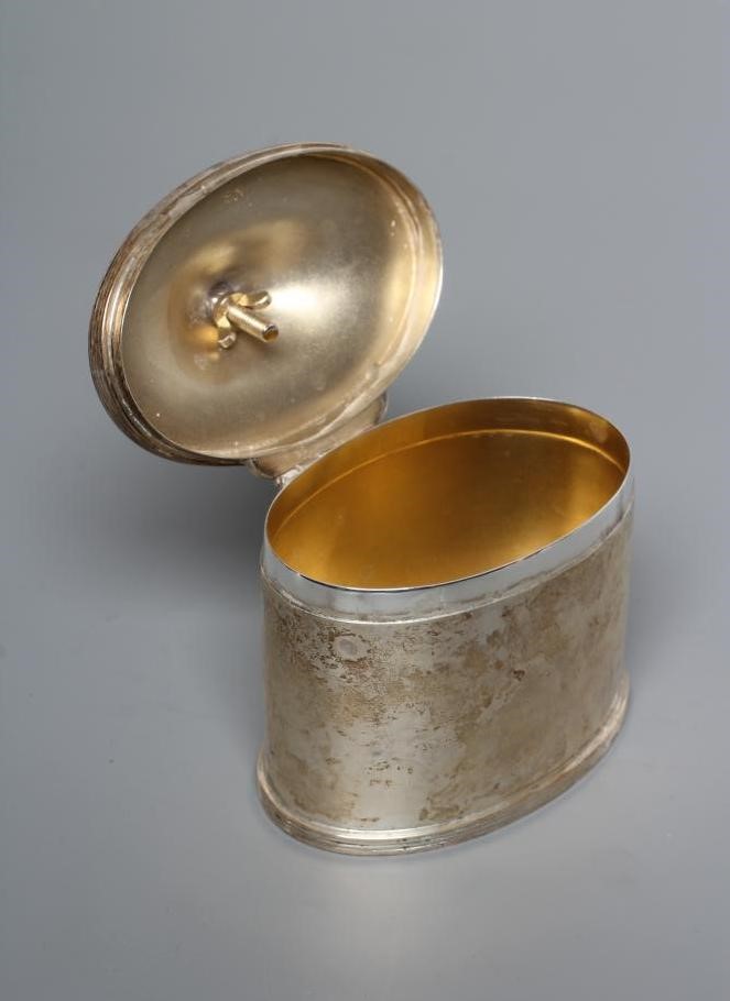 A SILVER TEA CANISTER, by Stokes & Ireland, Chester 1929, of oval section with cast and applied Image