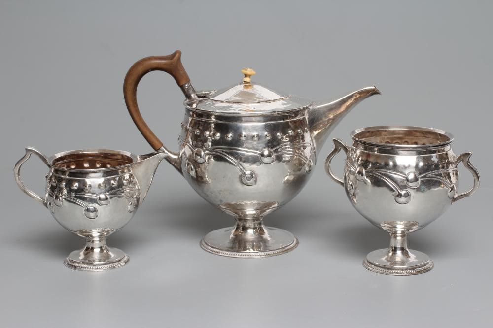 AN EDWARDIAN ARTS AND CRAFTS SILVER THREE PIECE TEA SERVICE Image