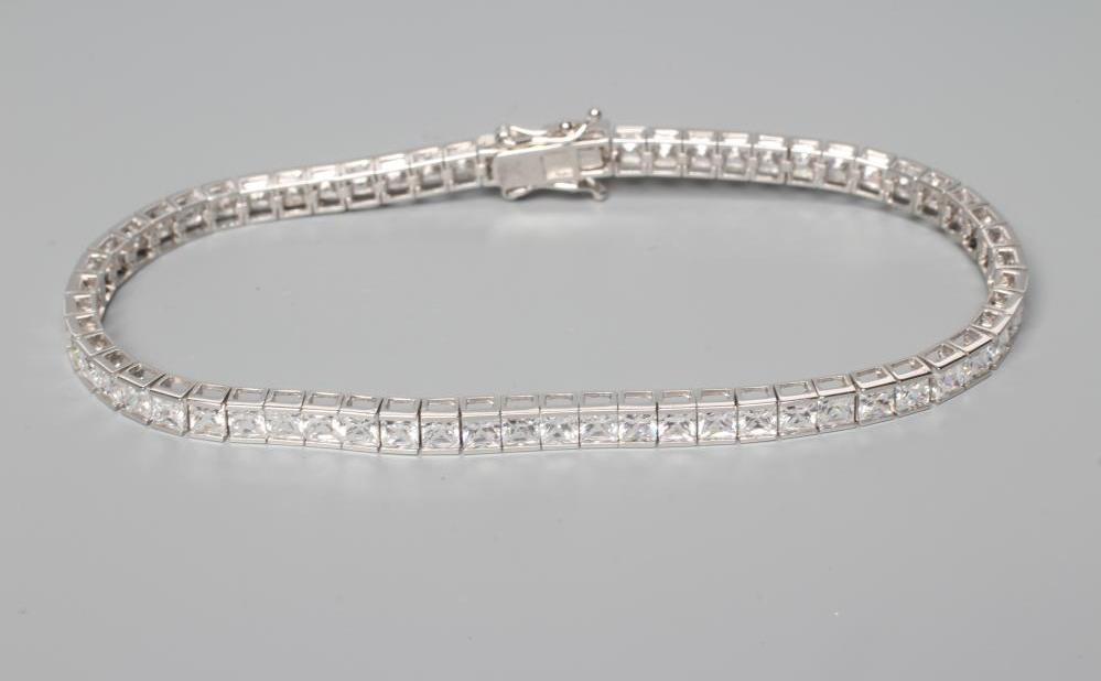 A TENNIS BRACELET, the sixty one cubic zirconia channel set to a plain white frame, stamped 375 Image