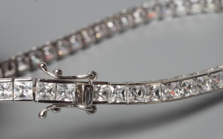 A TENNIS BRACELET, the sixty one cubic zirconia channel set to a plain white frame, stamped 375 Image