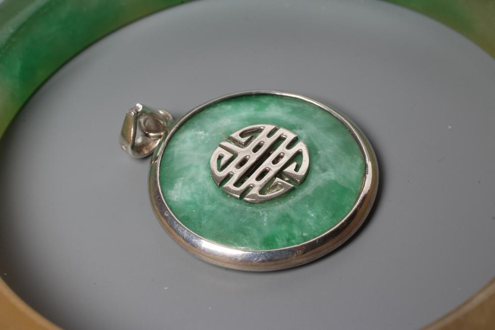 A POLISHED JADE BANGLE of D form, 37g, together with a silver mounted jade Shou pendant, stamped 925 Image