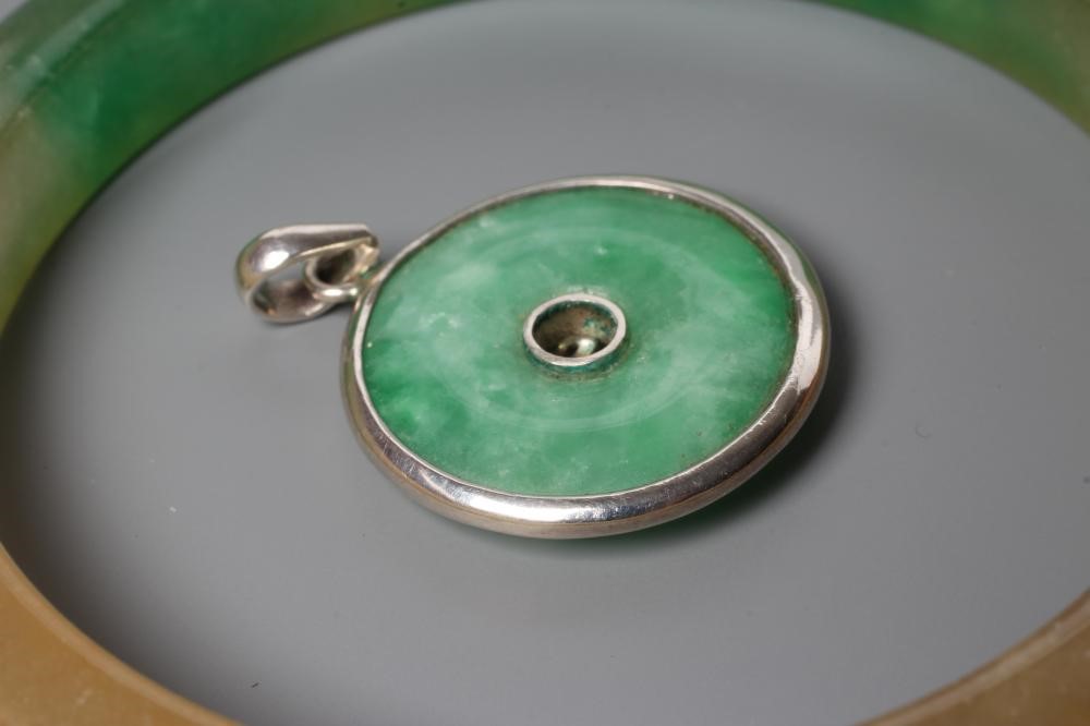 A POLISHED JADE BANGLE of D form, 37g, together with a silver mounted jade Shou pendant, stamped 925 Image