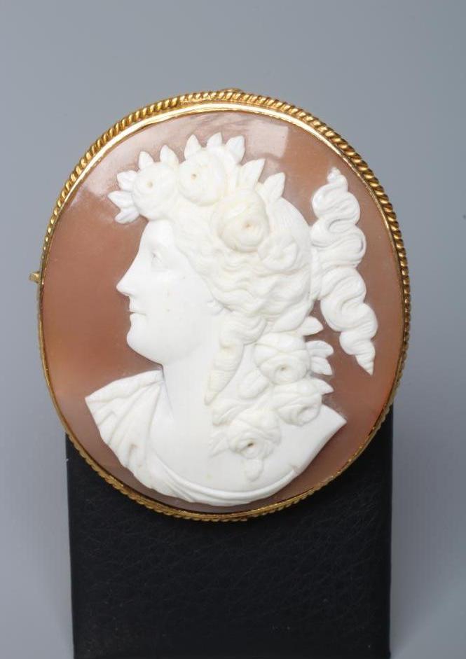 A SHELL CAMEO BROOCH carved with the head and shoulders of a young lady with flowers in her curled Image