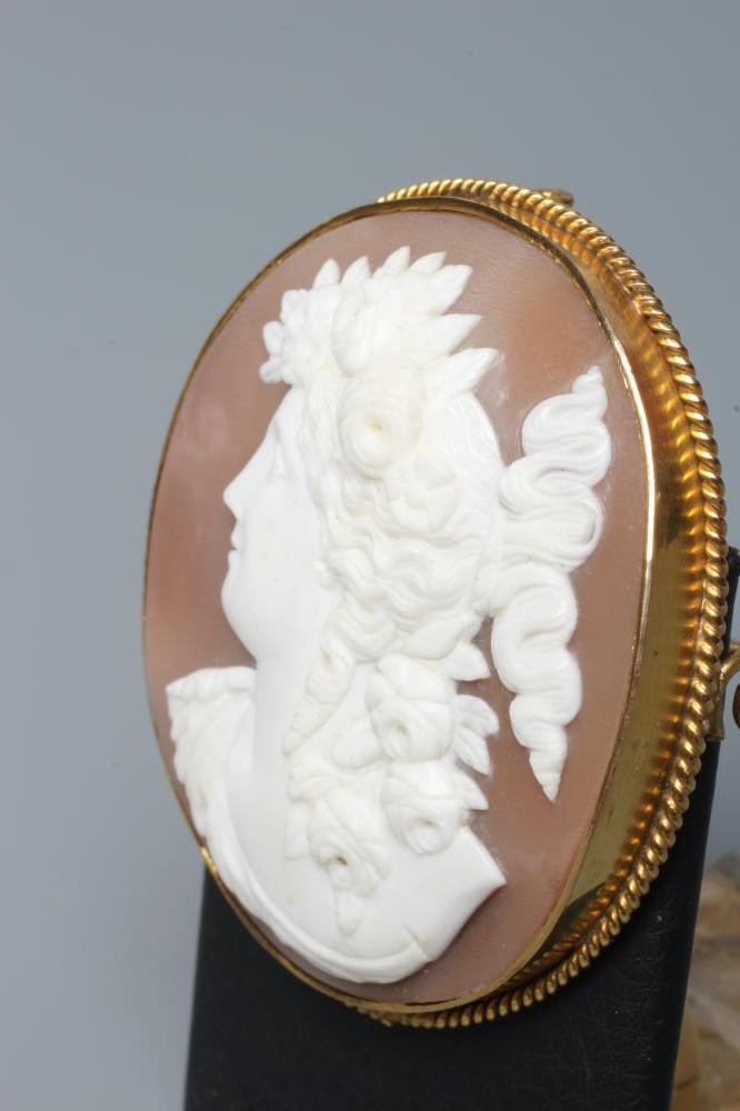 A SHELL CAMEO BROOCH carved with the head and shoulders of a young lady with flowers in her curled Image