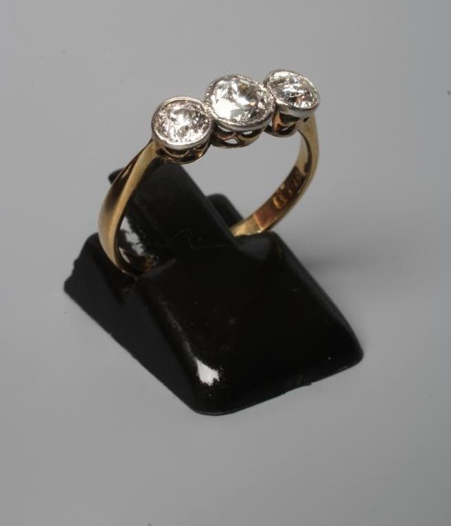 A THREE STONE DIAMOND RING, the old cut stones collet set to a plain shank stamped 18ct, size N Image