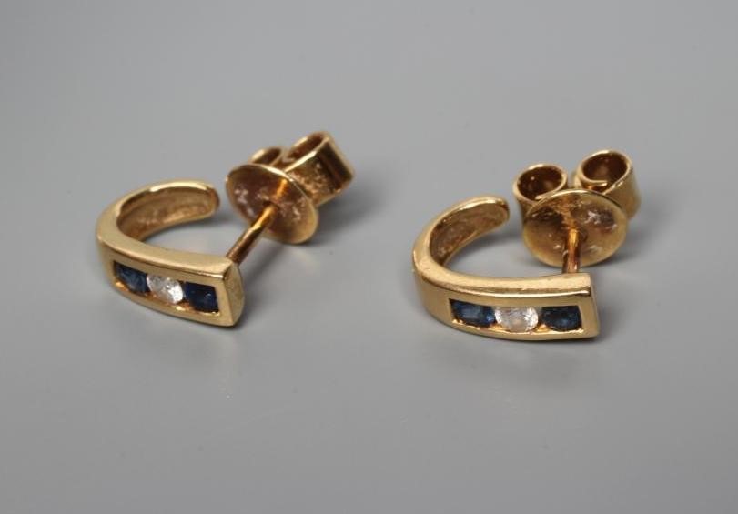 A SMALL PAIR OF SAPPHIRE AND DIAMOND HALF HOOP EAR STUDS, channel set with a diamond flanked by two Image