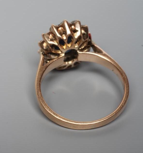 A SAPPHIRE AND DIAMOND CLUSTER RING, the oval facet cut sapphire claw set to a border of fourteen Image