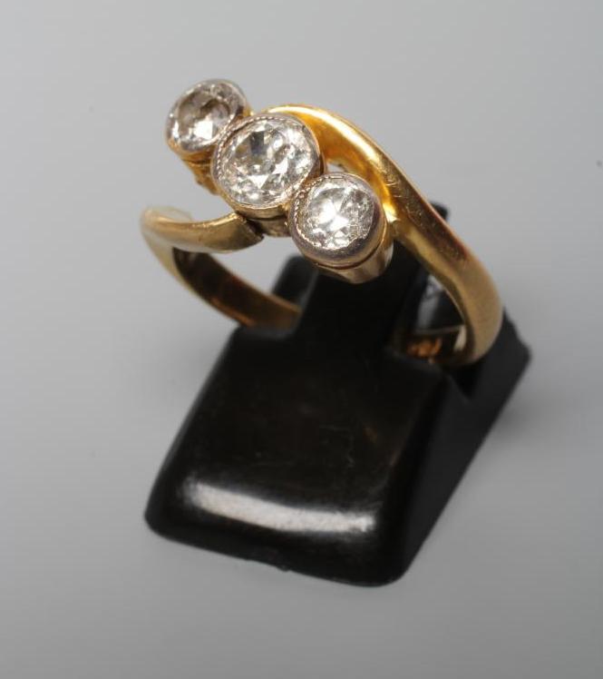 A THREE STONE DIAMOND CROSSOVER RING, the mix cut stones totalling approximately 1ct, collet set to Image