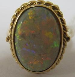 AN OPAL DRESS RING, the oval cabochon polished stone collet set to a rope twist mount and plain Image