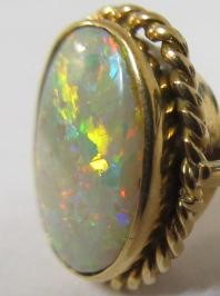 AN OPAL DRESS RING, the oval cabochon polished stone collet set to a rope twist mount and plain Image