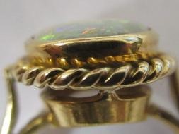 AN OPAL DRESS RING, the oval cabochon polished stone collet set to a rope twist mount and plain Image