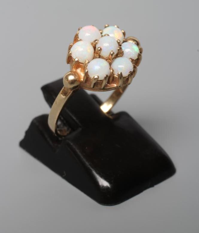 A SEVEN STONE OPAL CLUSTER RING, the circular cabochon polished stones claw set to a plain 9ct gold Image