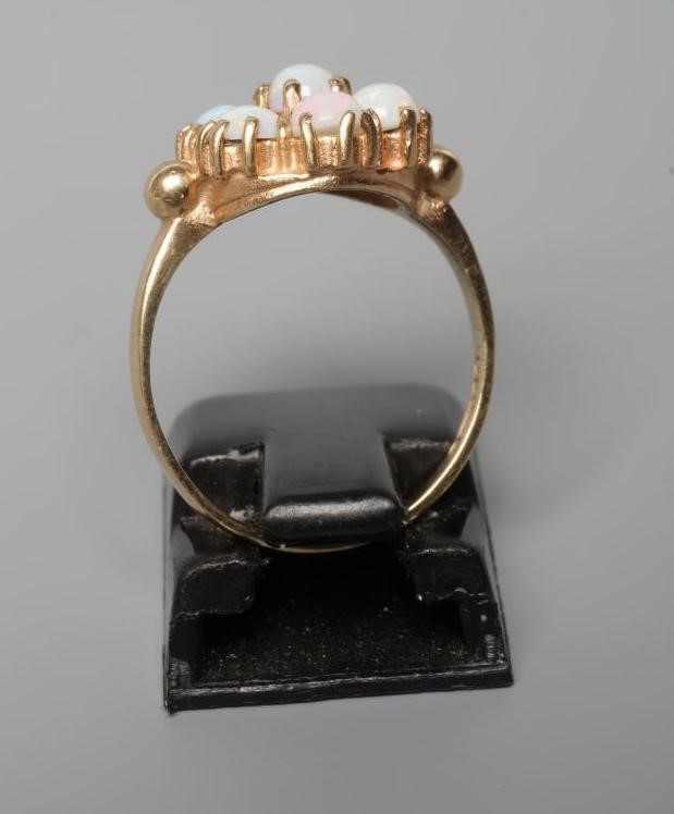 A SEVEN STONE OPAL CLUSTER RING, the circular cabochon polished stones claw set to a plain 9ct gold Image