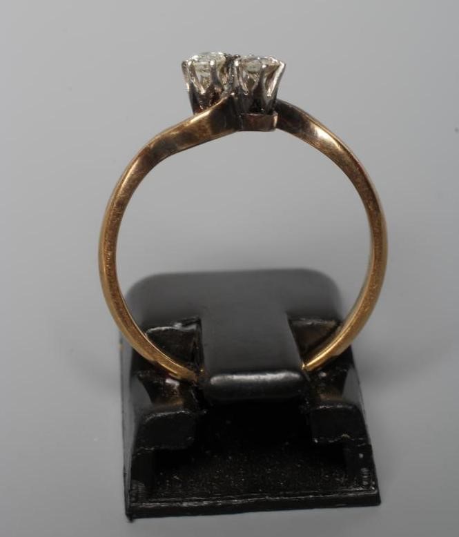 A TWO STONE DIAMOND CROSSOVER RING, the small old brilliant cut stones claw set to a plain shank Image