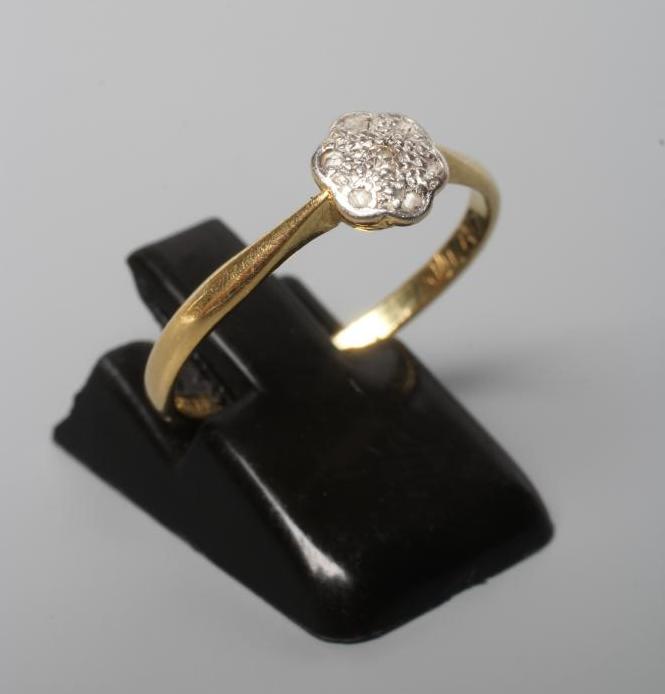 A SEVEN STONE DIAMOND CLUSTER RING, the small rose cut stones illusion set in platinum to a plain Image