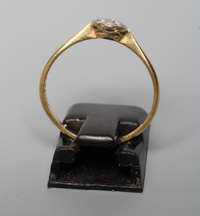 A SEVEN STONE DIAMOND CLUSTER RING, the small rose cut stones illusion set in platinum to a plain Image