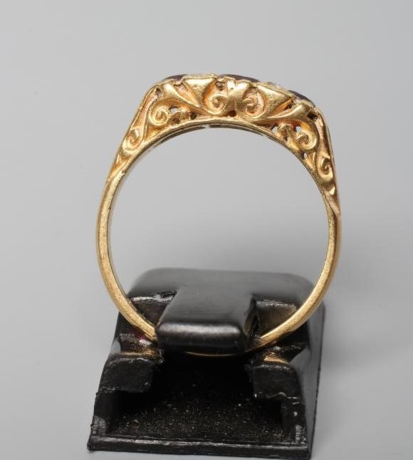 A THREE STONE GARNET RING, the graduated circular stones in carved mount with two pairs of rose cut Image