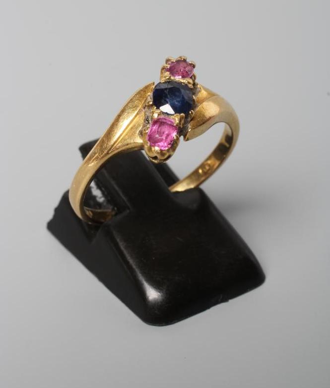 A SAPPHIRE AND GARNET THREE STONE CROSSOVER RING Image