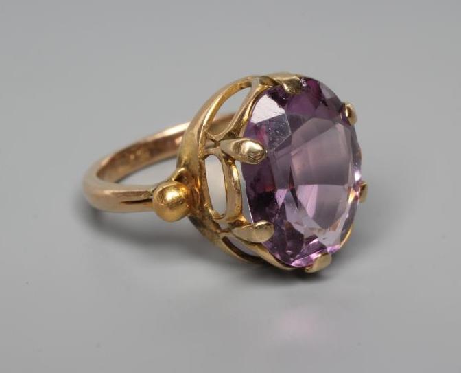 AN AMETHYST DRESS RING, the oval facet cut stone claw set to bead shoulders and a plain shank Image