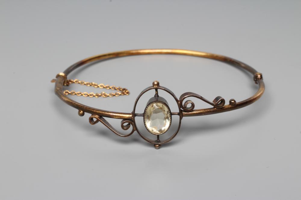 A VICTORIAN STIFF HINGED BANGLE, the upper section centred by an open back collet set oval facet cut Image