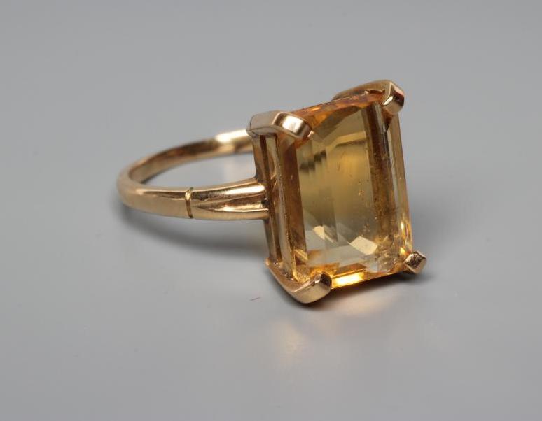 A CITRINE COCKTAIL RING, the rectangular cut stone claw set to reeded shoulders and a plain shank Image