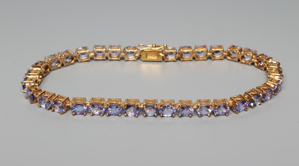 A TANZANITE TENNIS BRACELET, the thirty four oval facet cut stones claw set to a plain frame, the Image
