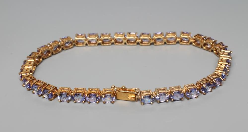 A TANZANITE TENNIS BRACELET, the thirty four oval facet cut stones claw set to a plain frame, the Image