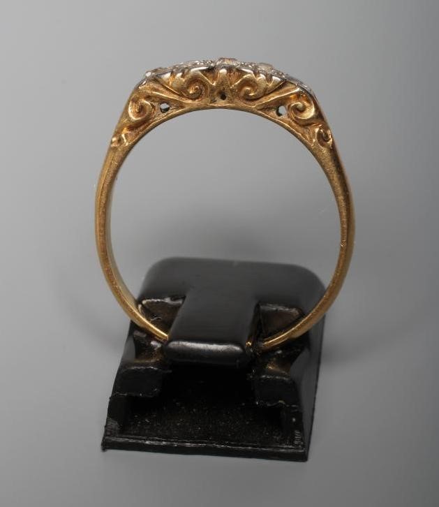 A VICTORIAN FIVE STONE DIAMOND RING, the graduated old cut stones point set to carved shoulders and Image