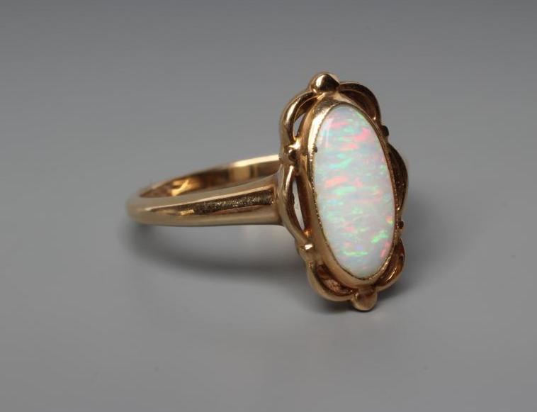 AN OPAL DRESS RING, the oval cabochon polished stone collet set to an open wavy mount and plain Image