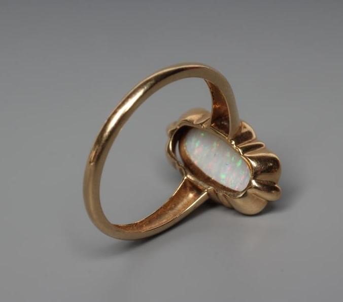 AN OPAL DRESS RING, the oval cabochon polished stone collet set to an open wavy mount and plain Image