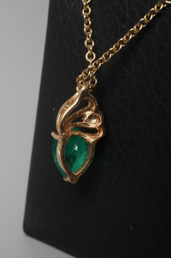 AN EMERALD PENDANT, the pear cut stone claw set to a plain unmarked frame below a triple bale set Image