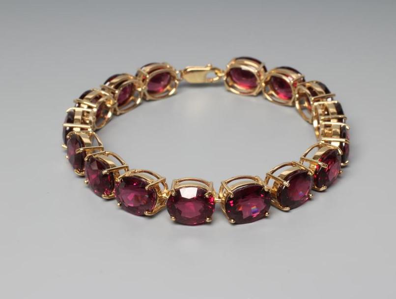 A GARNET BRACELET, the sixteen oval facet cut stones claw set to a plain frame with lobster clasp Image